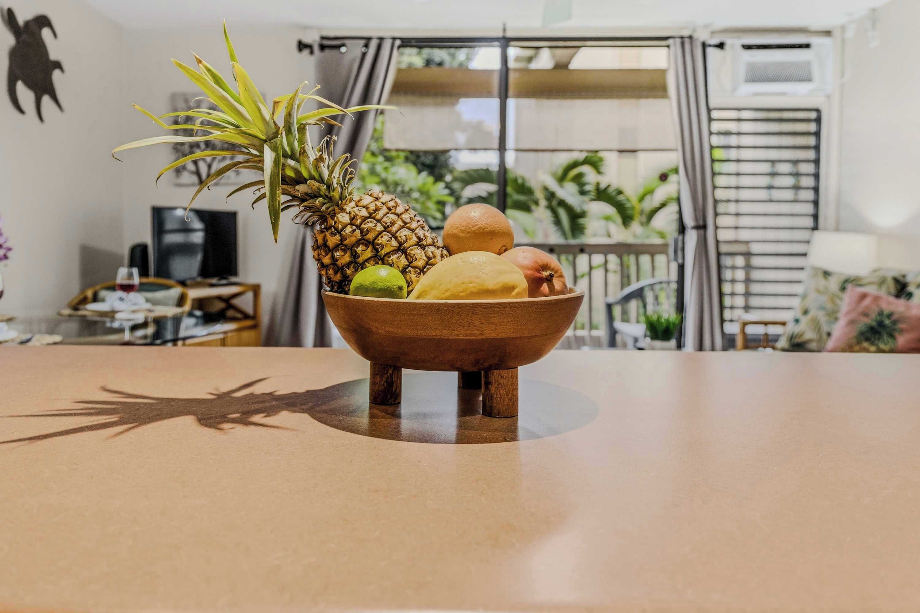 Eine Holzkugel mit Früchten auf einem Tisch, ein Fernseher und Blick auf einen Balkon mit Pflanzen.
