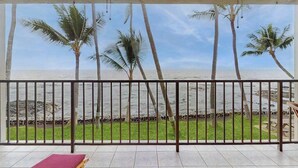Ein Zimmer mit Meerblick, Palmen und einem Balkon.