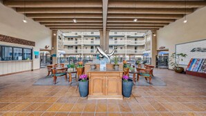 A spacious lobby with a central reception desk, multiple seating areas, and a view of the building's exterior balconies. - *NEW* Oceanfront Kona Retreat Near Lyman's Surf Spot (Kailua-Kona)