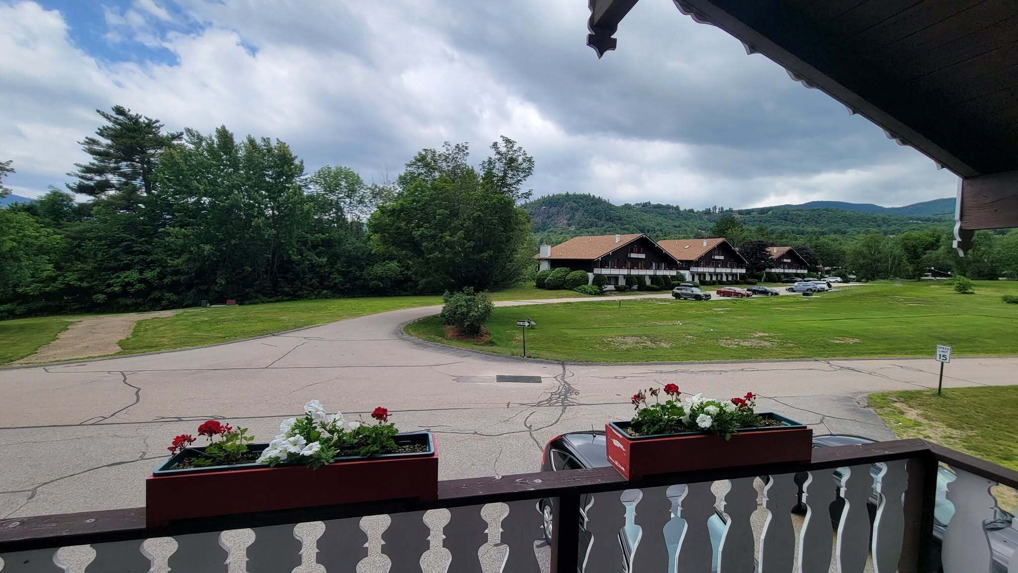 A hotel with a paved driveway, a lawn, and a mountain backdrop.
