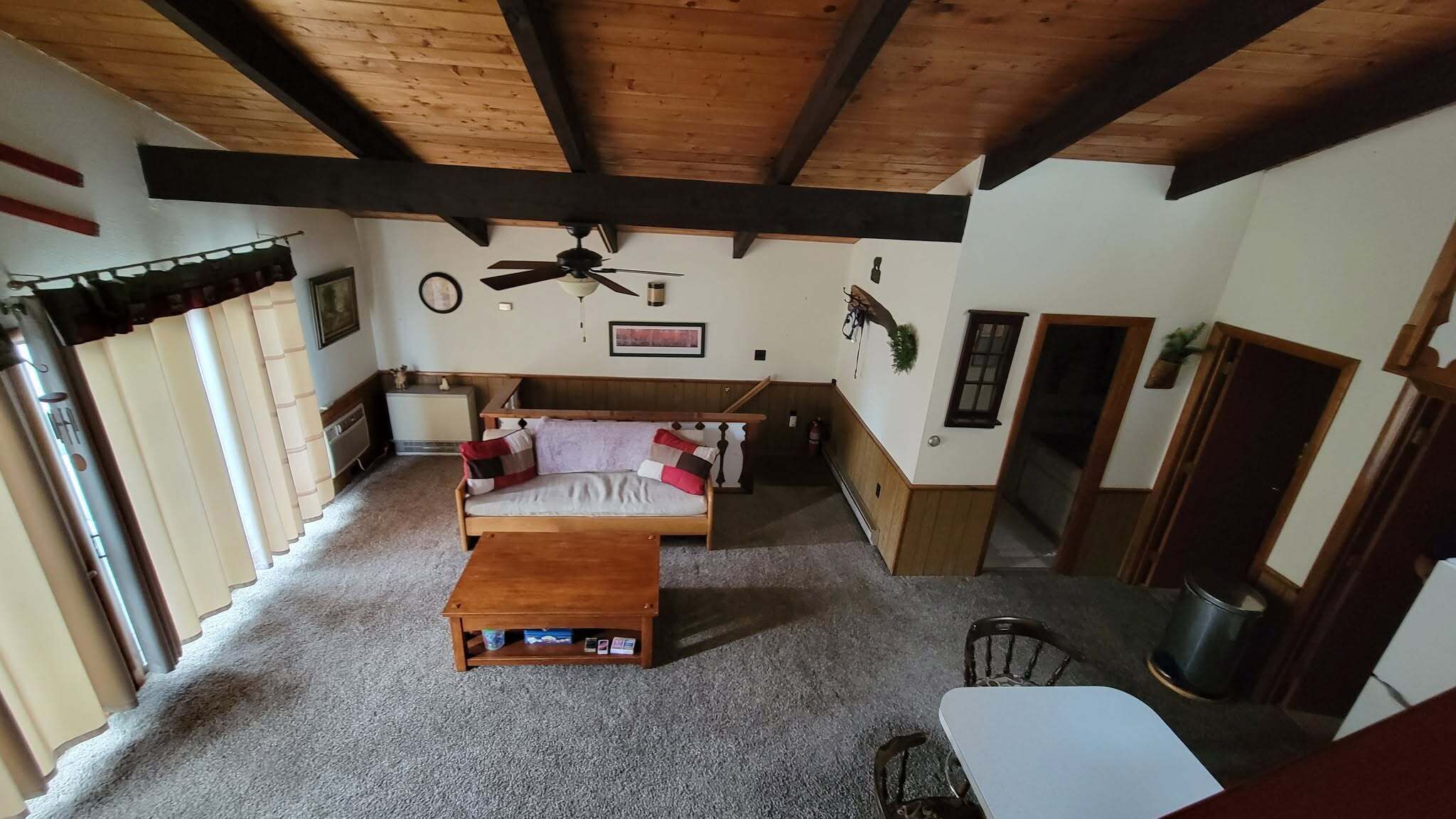 A cozy living room with a wooden ceiling, a sofa, a coffee table, and a dining area.
