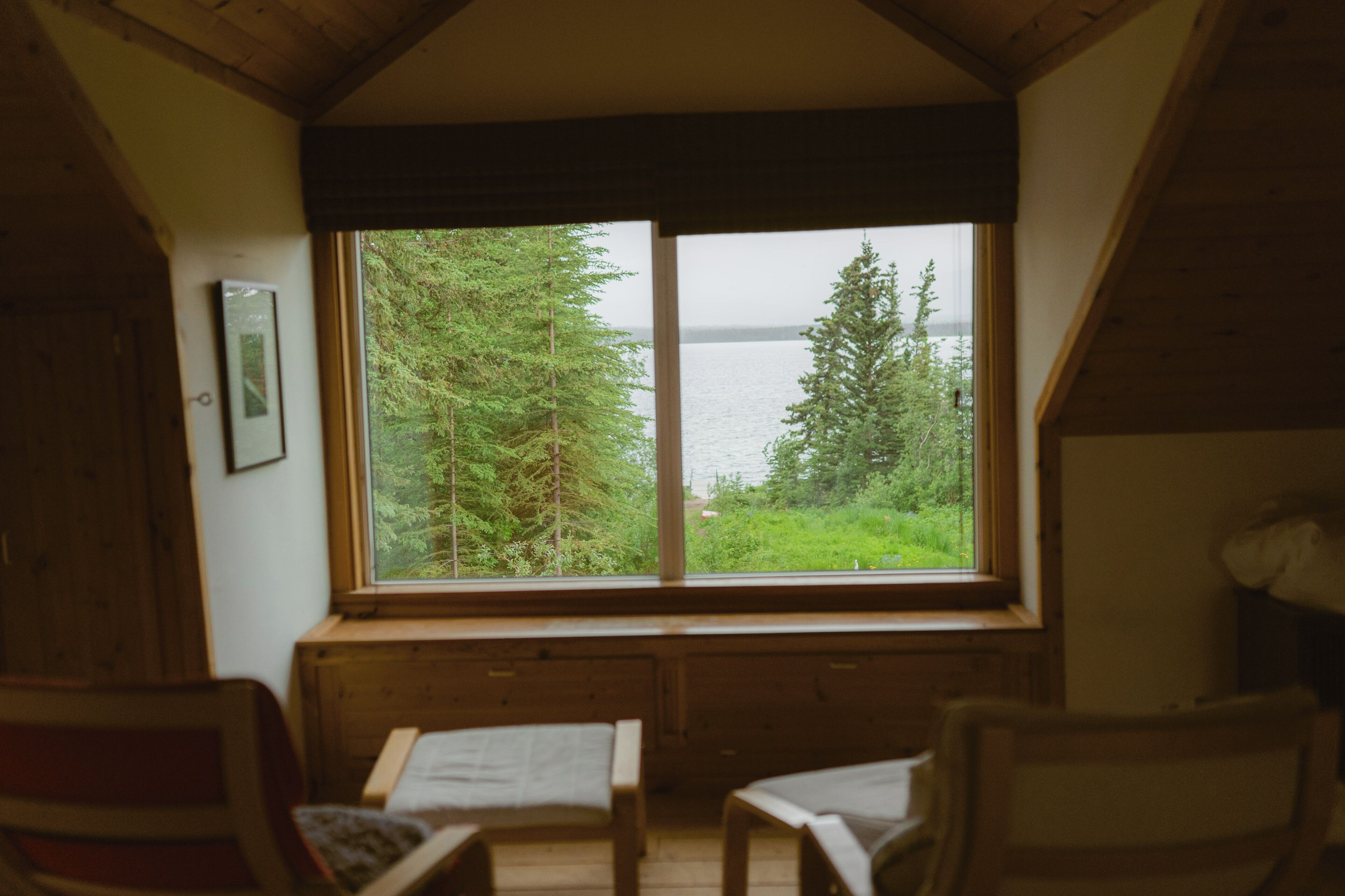 A cabin with a large window overlooking a forest and a body of water.