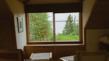 A cabin with a large window overlooking a forest and a body of water.