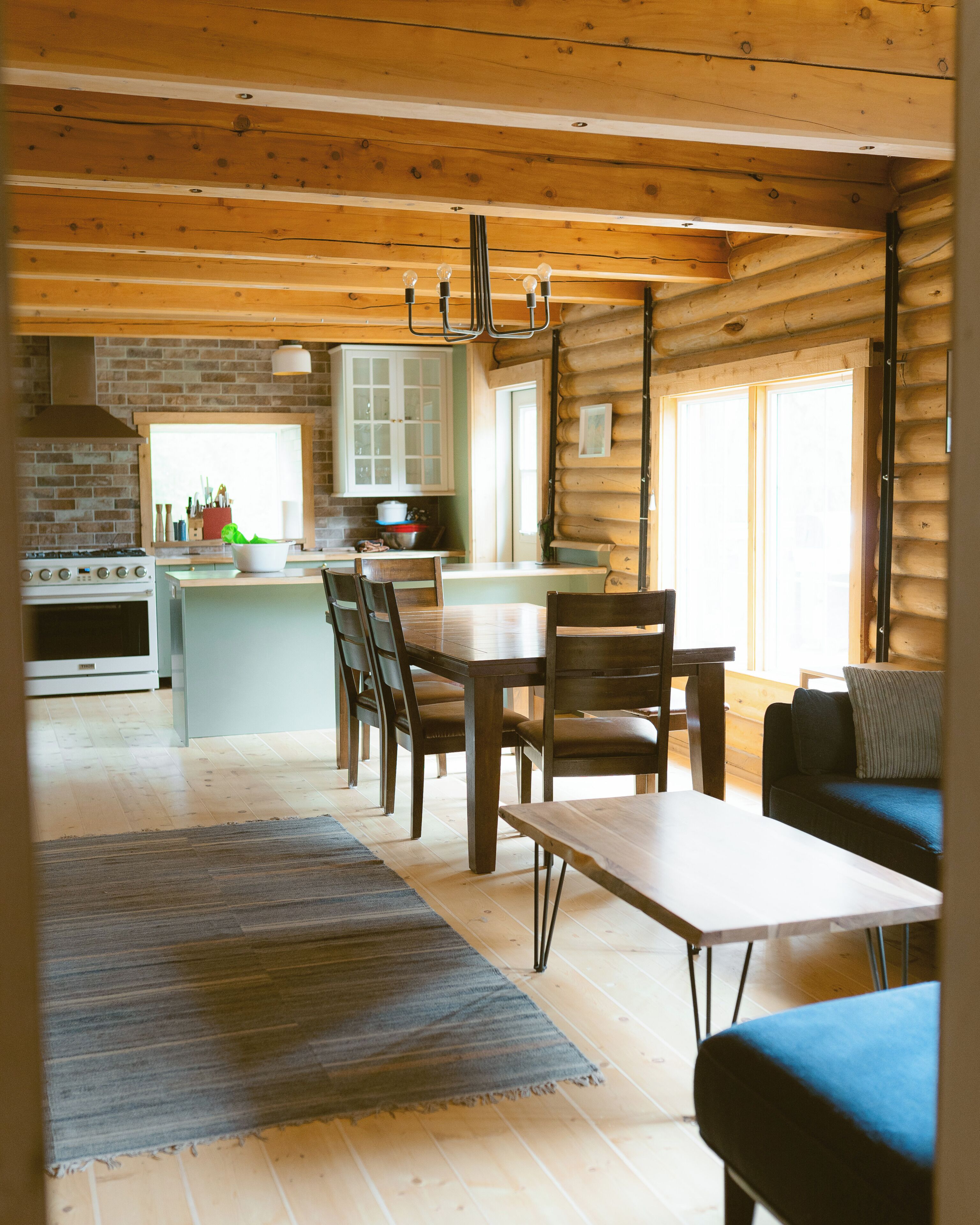 A log cabin interior with a kitchen, dining area, and living space.