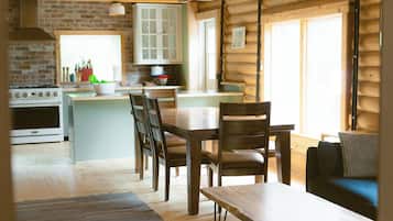 A log cabin interior with a kitchen, dining area, and living space.