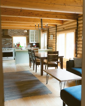 Interior de una cabaña de troncos con cocina, comedor y sala de estar.