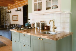 A kitchen with a wooden countertop, a sink, and cabinets.