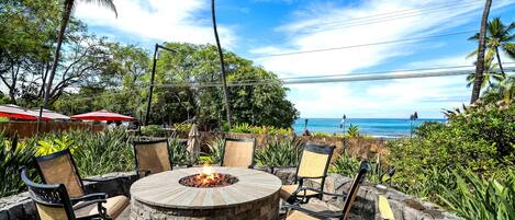 An outdoor seating area with a fire pit, stone walls, and chairs.