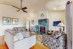 A living room with a sofa, a patterned armchair, a fireplace, and a ceiling fan. - *NEW* Fall Special Mauna Kea Views and Family Space in Waimea (Waimea)