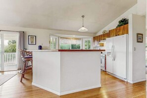 A modern kitchen with a central island, white cabinetry, and a view to the outside. - *NEW* Fall Special Mauna Kea Views and Family Space in Waimea (Waimea)