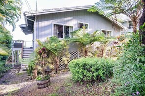 A house with a garden, a wooden deck, and a fence.