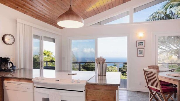 Une cuisine avec vue sur l’océan, un coin repas avec une table et des chaises, et un plafond en bois.