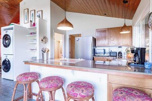 Una cocina con armarios de madera, lavadora integrada, microondas y cafetera.