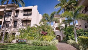 A multi-story building with a courtyard, palm trees, and a sign indicating 'Banyan Tower.' - *New* Fall Sale Renovated Waikoloa Condo Near A-Bay (Waikoloa)
