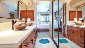 A modern bathroom with a large mirror, wooden cabinets, a bed, and a view of the outdoors. - *New* Fall Sale Renovated Waikoloa Condo Near A-Bay (Waikoloa)