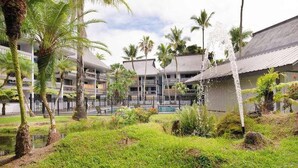 A hotel courtyard with palm trees, a water feature, and a pool. - *New* Fall Sale Hilo Water-View Condo with Lanai, Pool, and Koi Stream (Hilo)