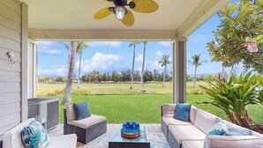 Un espace extérieur aménagé, abrité et doté de mobilier en osier, d’un ventilateur de plafond et d’une vue sur un terrain de golf.