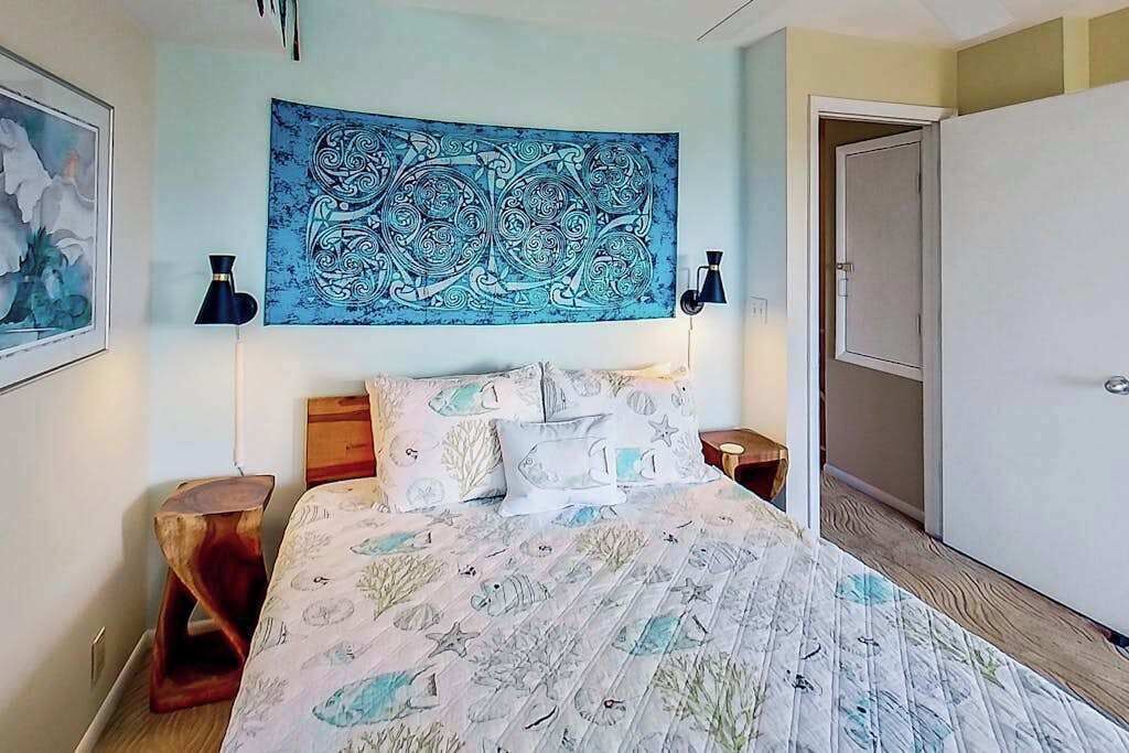Une chambre à coucher comprenant un lit, une tapisserie, une table de chevet, une lampe et une armoire.