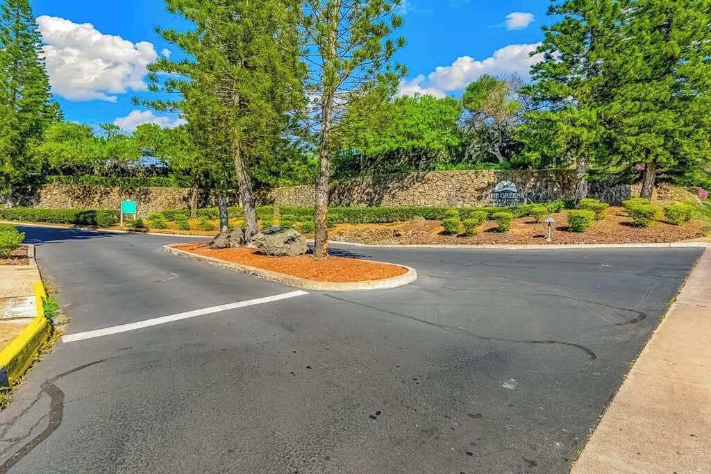 Une route avec un rond-point, des arbres et un mur de pierres.
