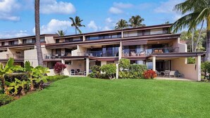 A multi-story hotel with balconies, a well-maintained lawn, and tropical plants. - *NEW* Kona Sunsets from a Ground Floor Ocean View Lanai (Kailua-Kona)