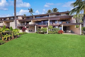 A multi-story hotel with balconies, a well-maintained lawn, and tropical plants. - *NEW* Kona Sunsets from a Ground Floor Ocean View Lanai (Kailua-Kona)
