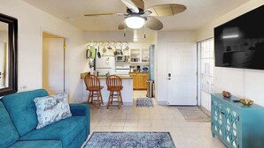 A living room with a sofa, a ceiling fan, and a kitchen area with a dining set. - *NEW* Fall $pecial Heated Pool, Hot Tub and Golf in Waikoloa Village (Waikoloa Village)