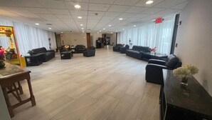 A spacious hotel lobby with a high ceiling, multiple seating areas, and a reception desk.