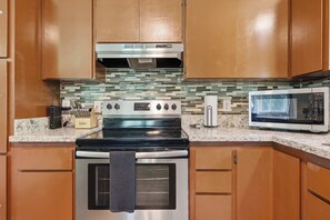 A kitchen with a stainless steel stove, a microwave, and wooden cabinets.