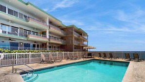 Un hotel con piscina, varios balcones y vista al océano.