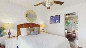 Un dormitorio con una cama grande, un ventilador de techo, un espejo en la pared y un cuadro enmarcado.