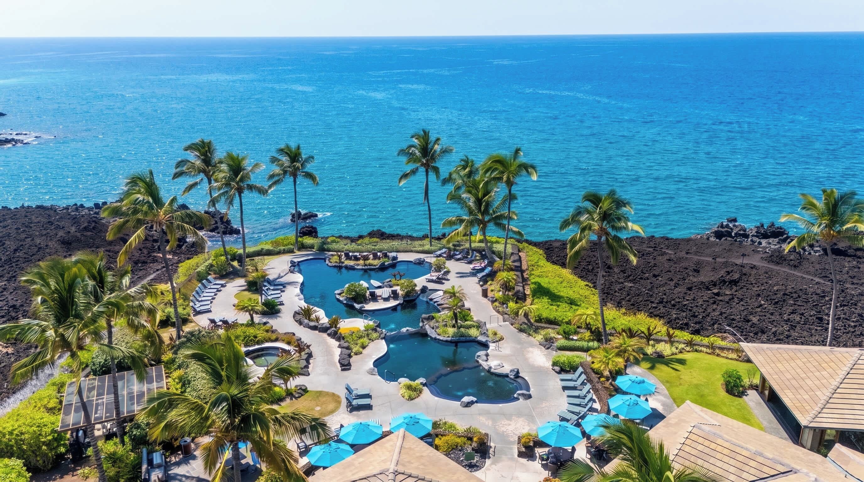 A resort with a pool area, lounge chairs, and a view of the ocean.