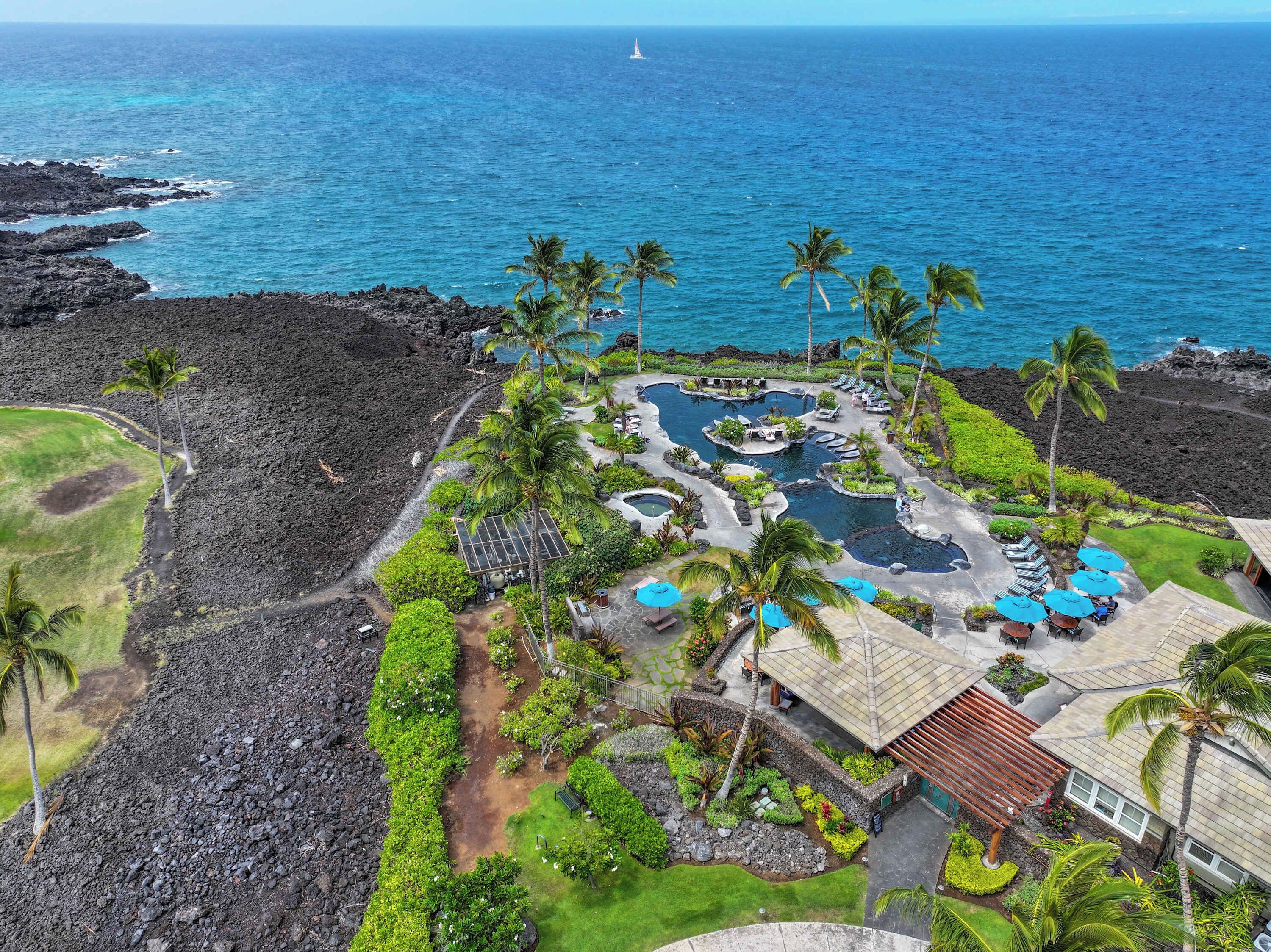 Ein Resort mit Poolbereich, Palmen und Blick auf den Ozean.