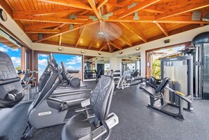 Un gimnasio con cintas de correr, máquinas de pesas y un techo con vigas de madera.