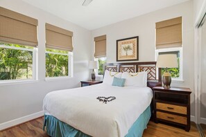A hotel room with a bed, two nightstands, a lamp, a picture frame, and windows with blinds.
