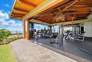An open-air gym with exercise equipment, a covered area, and a view of the outdoors.