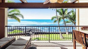 Ein Balkon mit Blick auf den Ozean, ein Deckenventilator und ein Holzstuhl.