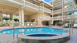 Un hotel de varios niveles con piscina, zona de estar exterior y un patio cubierto.