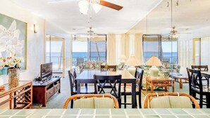 Una habitación amplia con zona de comedor, televisión y vista al océano.