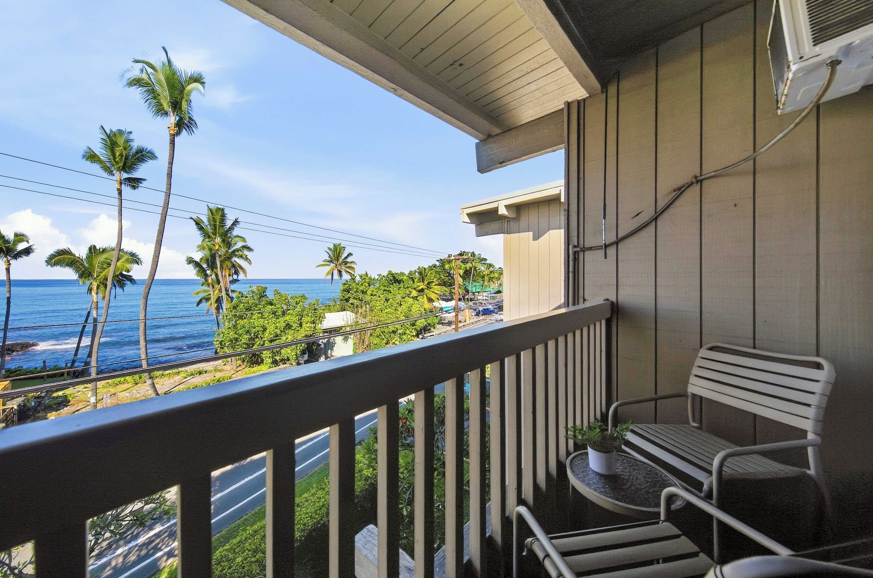 A balcony with a view of the ocean and palm trees.