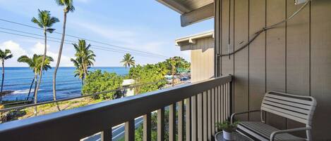 A balcony with a view of the ocean and palm trees.