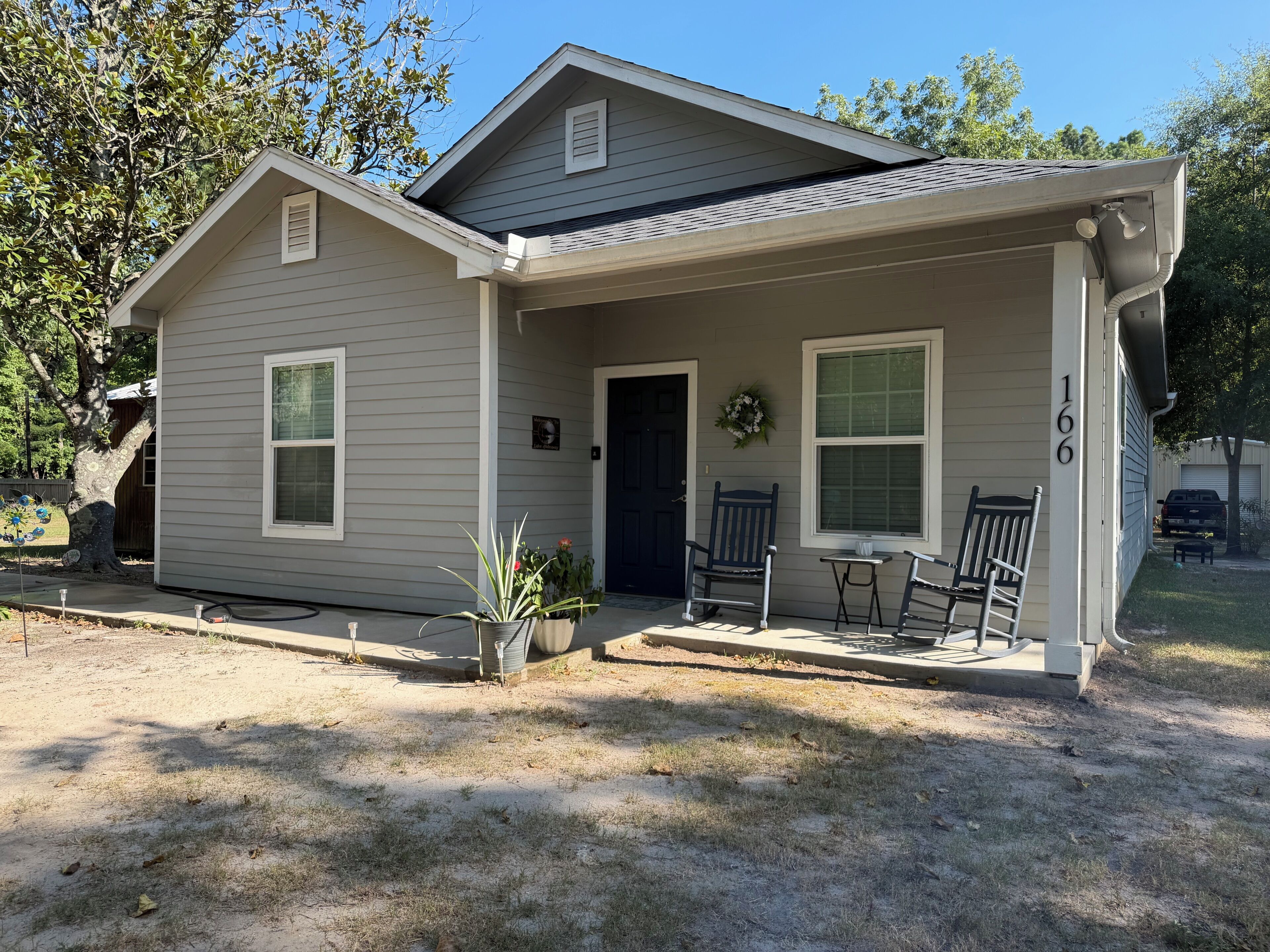 A single-story house with a front porch, a garage, and a number '166' on the side.