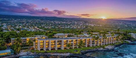 A resort with multiple buildings, a beachfront, and a cityscape in the background.