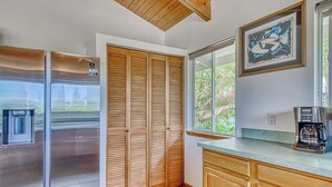 Una cocina con un refrigerador de acero inoxidable, gabinetes de madera, una cafetera y una ventana con vistas a la vegetación.