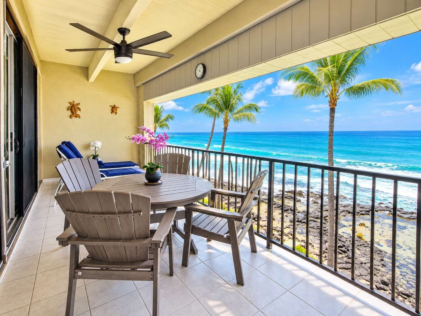 A balcony with a round table, chairs, and a ceiling fan.