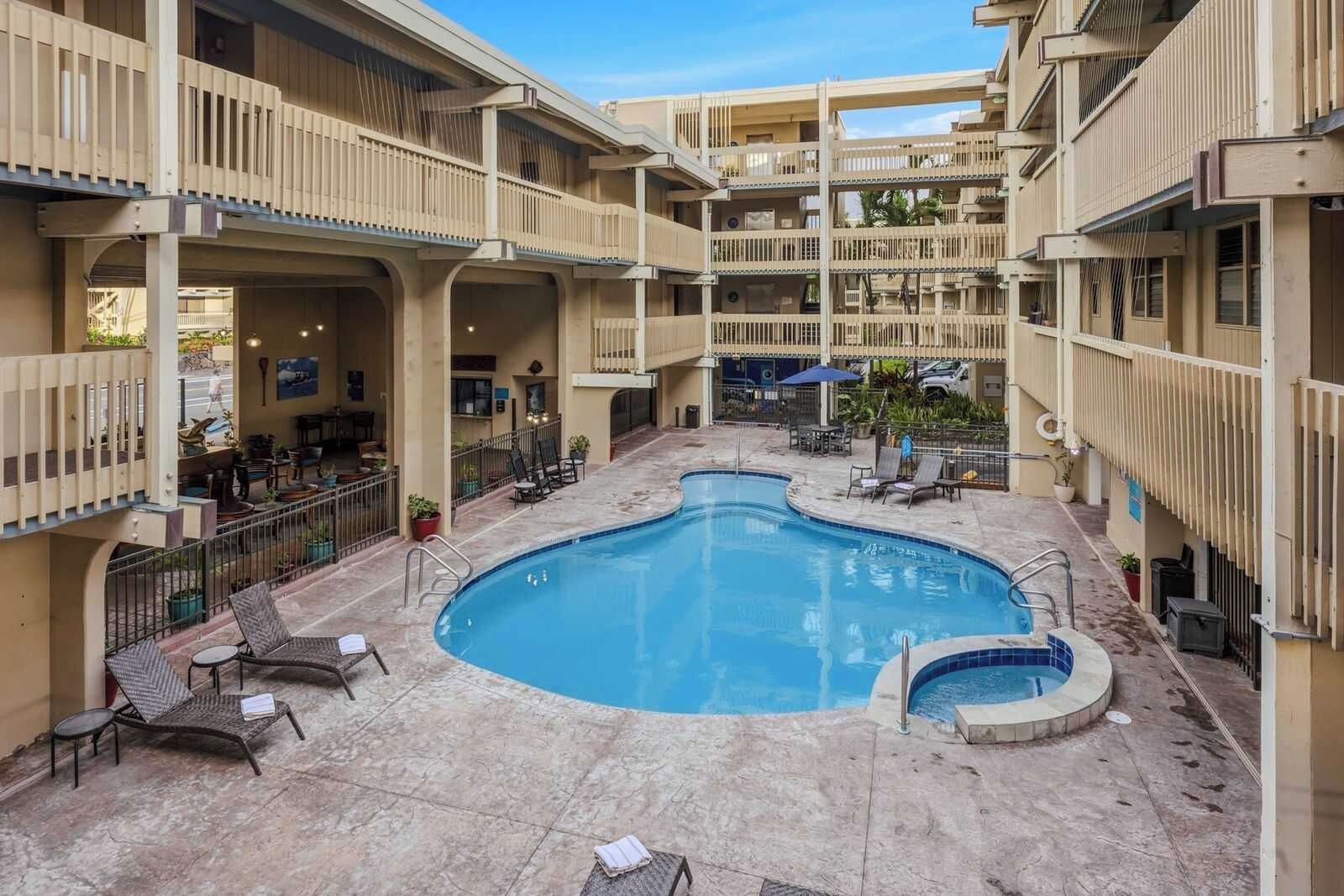 Un hotel a più livelli con piscina centrale, posti a sedere all'aperto e una zona patio coperta.
