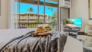Een hotelkamer met balkon, een bed, een televisie en een ontbijtbakje.