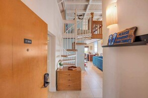A wooden door with a sign, a staircase, a blue sofa, and a wall-mounted sign. - Keauhou Family Oceanview w/ Loft, Pool, Spa, Yoga, Smart TV, Kitchen, BBQ, Beach (Kailua-Kona)