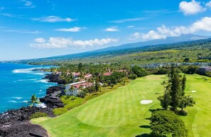 Ein Küsten-Golfplatz mit Blick auf das Meer und eine bergige Landschaft im Hintergrund.