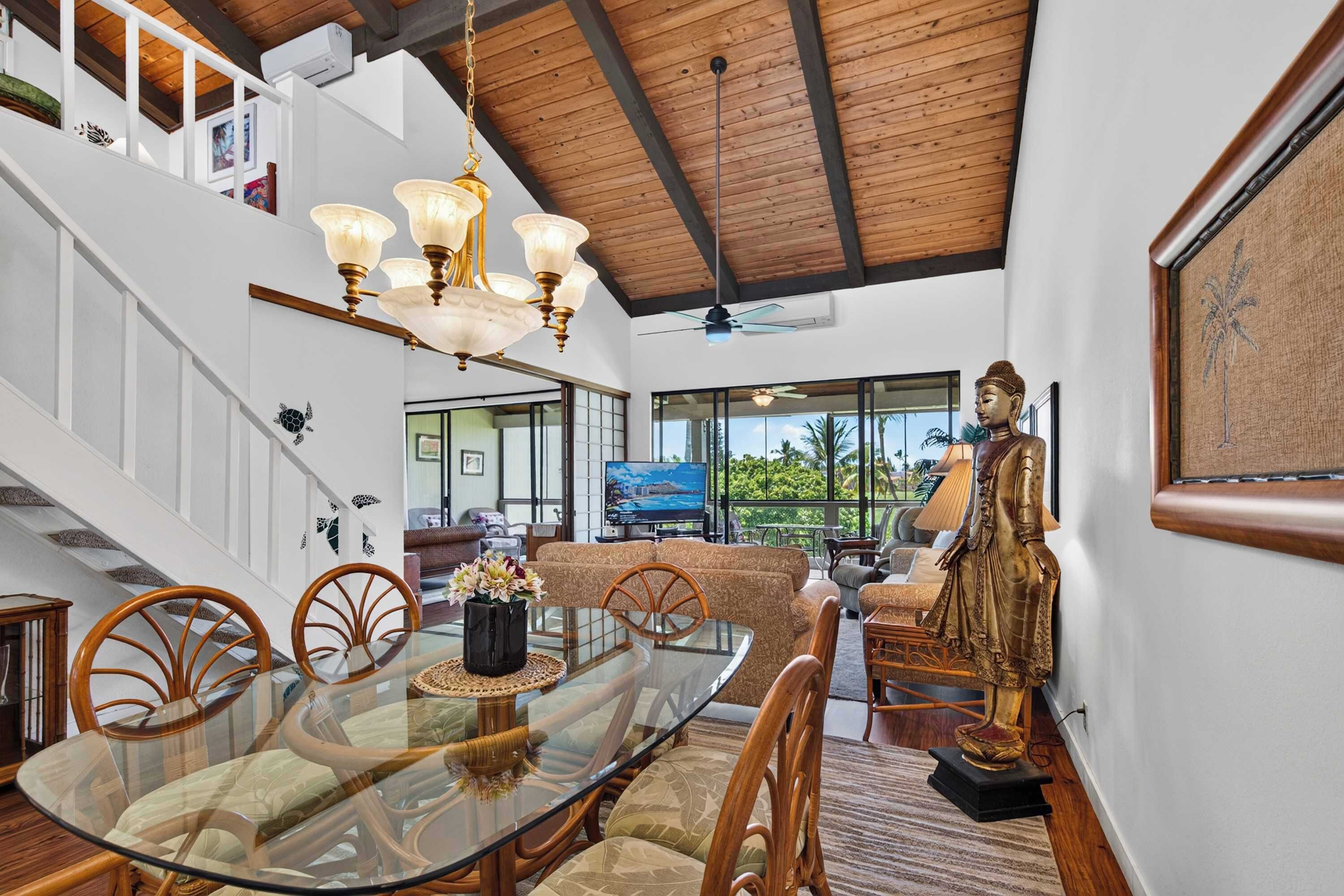 A spacious living area with a large dining table, comfortable seating, a Buddha statue, and a view of the outdoors.