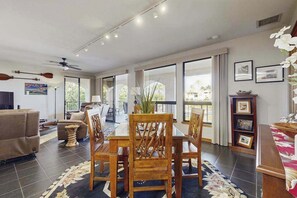 A spacious living area with a dining table, chairs, a sofa, and a TV. - New Walk to Waikoloa Beach from a Resort-Style Condo (Waikoloa)